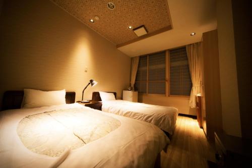 会津若松Aizu Higashiyama Onsen Tsuki no Akari的一间卧室设有两张床和窗户。
