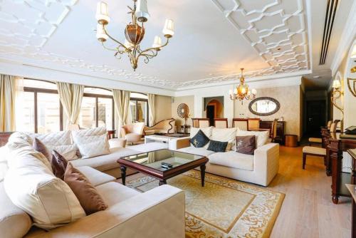 迪拜Zabeel Saray Royal Residences Lagoon Villa的客厅配有白色家具和吊灯。