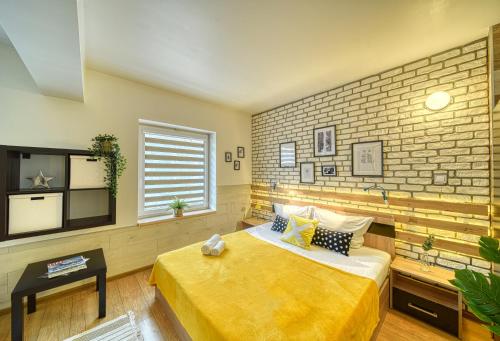旧扎戈拉Fox Rooms Aparthotel的一间卧室设有黄色的床和砖墙