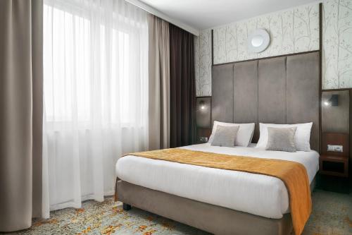 克拉科夫Metropolo by Golden Tulip Krakow的一间卧室设有一张大床和一个大窗户