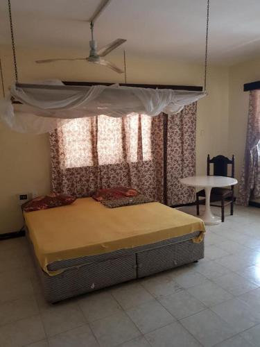 马林迪Surahi Restaurant & Guest House的一间卧室配有一张带天蓬和桌子的床