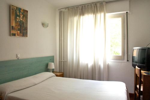 安道尔城西拉库萨酒店的一间卧室设有一张床、一个窗口和一台电视