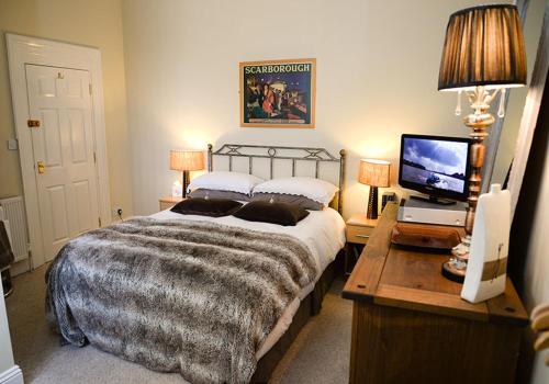 布里德灵顿The Villa Bridlington的一间卧室配有一张床和一张书桌及电视