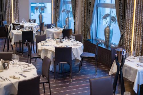 苏黎世克朗尤特斯特拉斯酒店的一间设有白色桌椅和窗户的用餐室