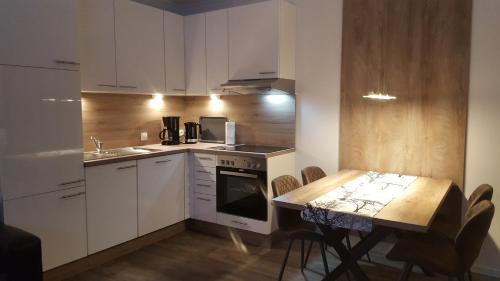 OberlangenEmsgold的厨房配有白色橱柜和桌椅