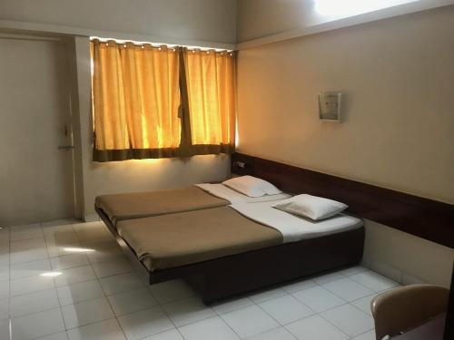 浦那Maurya Residency的一间小卧室,配有床和窗户