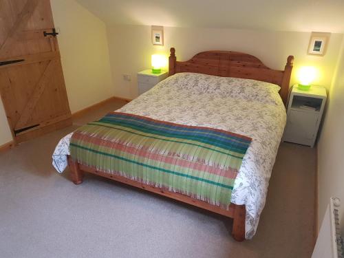 兰达弗里Seren Loft - Cynghordy, Llandovery的一间卧室配有木床和两盏灯