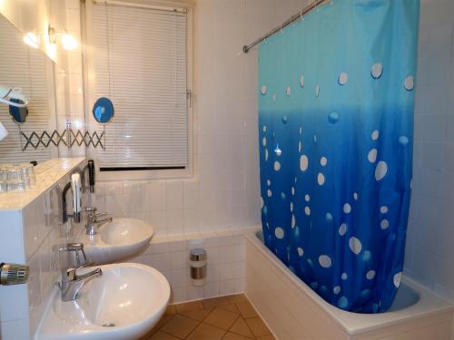 莱比锡莱比锡阿尔德酒店的浴室设有2个水槽和蓝色的浴帘