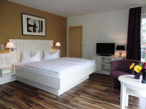 塞巴特阿尔贝克德利亚维尔旅馆的卧室配有白色的床和紫色椅子
