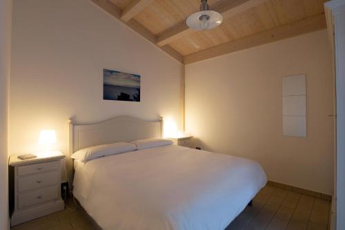 TorrenovaAgricampeggio Alessandra的卧室配有白色的床和两盏灯。