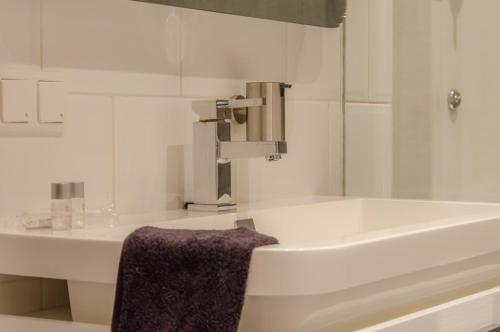 吕伐登B&B de Ferver的浴室设有水槽、浴缸和紫色毛巾