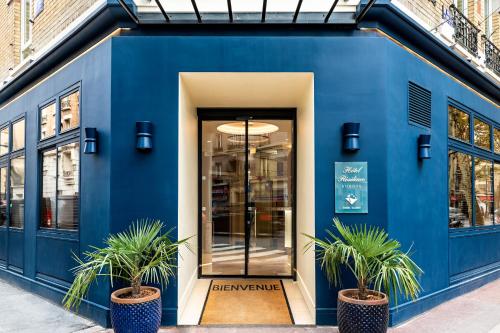 克利希Hotel Residence Europe & Spa的蓝色的建筑,前面有两株盆栽植物