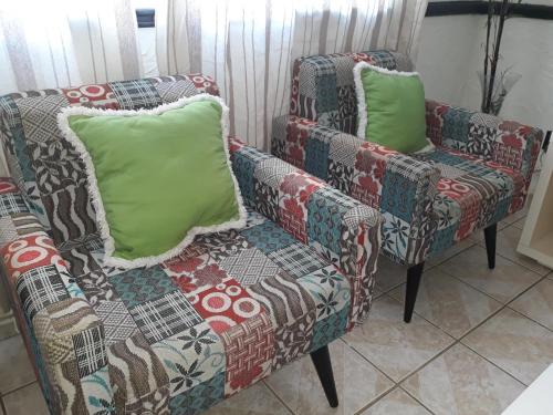 萨尔瓦多Apto Inteiro Stiep的一张沙发和两张带绿色枕头的椅子