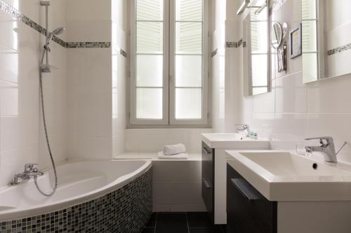 波城The Originals Boutique, Villa Montpensier, Pau (Inter-Hotel)的白色的浴室设有两个水槽、一个浴缸和一个浴缸。
