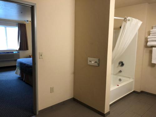 伍德伯恩伍德本速8酒店的客房设有带淋浴和浴缸的浴室。