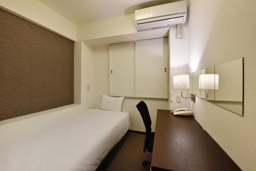 大阪关西酒店的一间卧室配有一张床和一张带电话的书桌
