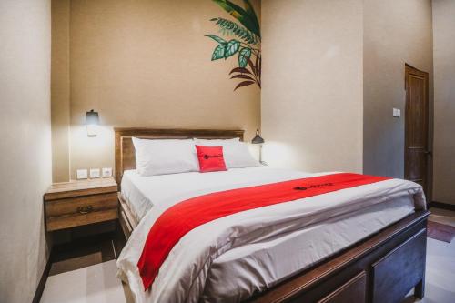 雅加达RedDoorz Plus near Mall Slipi Jaya的一间卧室配有一张带红色毯子的大床