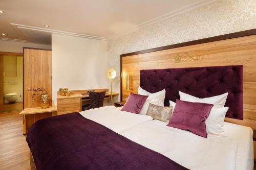 福森施洛斯科隆酒店的卧室配有一张带紫色枕头的大型白色床。