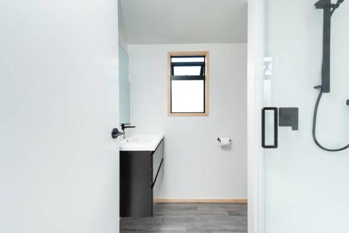 陶朗加Cozy Tiny House Hideaway的白色的浴室设有水槽和窗户。
