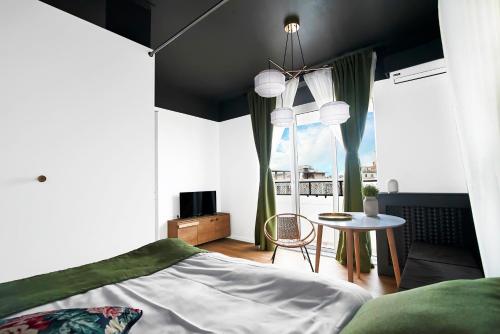 布加勒斯特Downtown by CityLife Suites的一间卧室配有一张床、一张桌子和一个窗户。