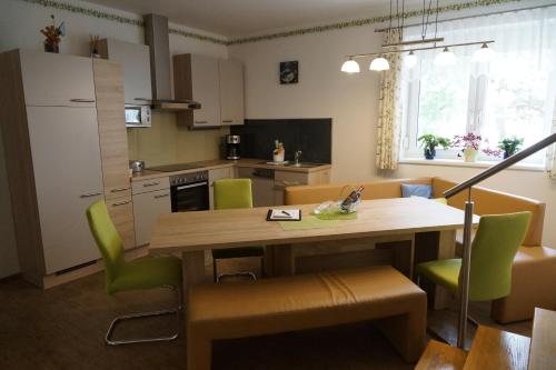 门希霍夫Zur Weinlaube的厨房以及带木桌和绿色椅子的用餐室。