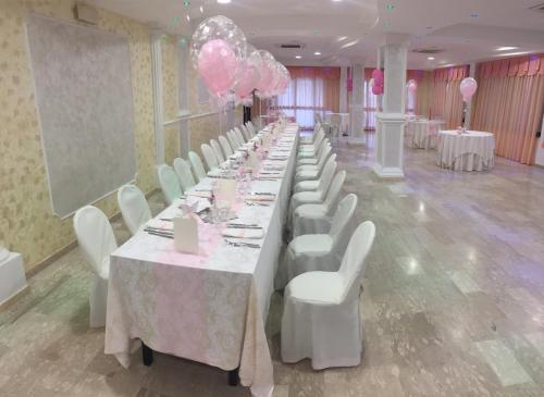 Zungri贝尔维德住宿加早餐酒店的一排桌子,上面有白色的椅子和粉红色的气球