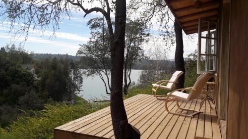 拉佩尔湖Cabaña de Adobe en Lago Rapel的湖景木制甲板,配有两把椅子