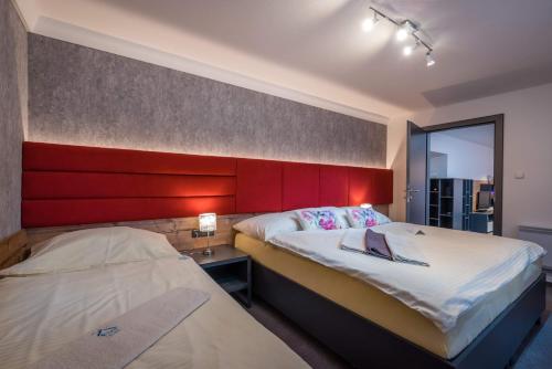 诺维斯莫克维克Apartman Smokovec的一间卧室设有两张床和红色床头板