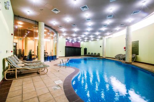 奥朱贝尔Karan Sharq for Hotel Apartment的游泳池位于酒店带躺椅的房间内,游泳池