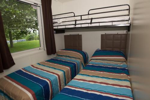 多尔梅莱托翡翠露营地的带窗户的客房内的两张双层床