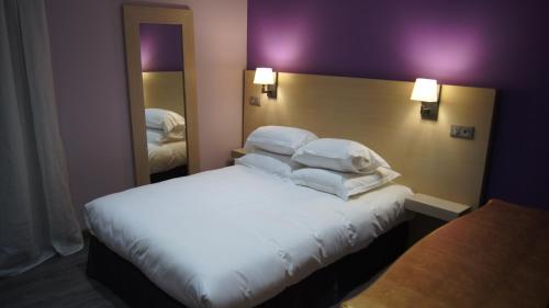 阿雅克修科瓦尔布朗克酒店的一间卧室配有带白色床单和枕头的床。