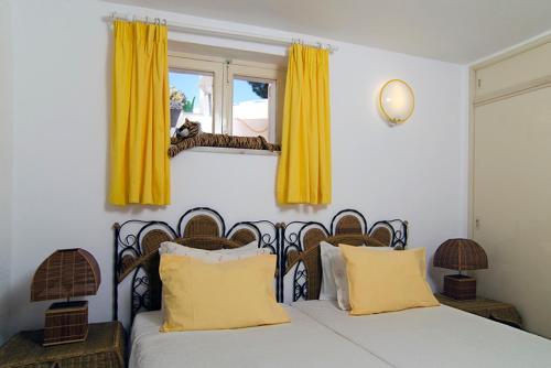 费拉古多Vila Monte Luz的一间卧室配有一张带黄色窗帘的床和一扇窗户