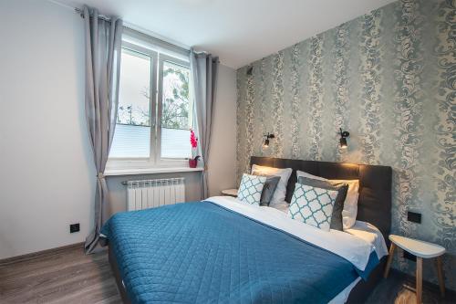 罗兹Apartament Manufaktura的一间卧室设有蓝色的床和窗户。