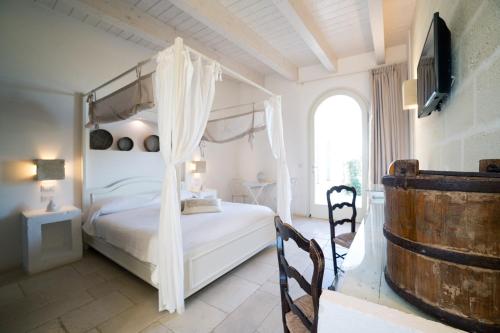 鲁蒂利亚诺Masseria Agrituristica Lama San Giorgio的卧室配有白色的天蓬床和窗户。