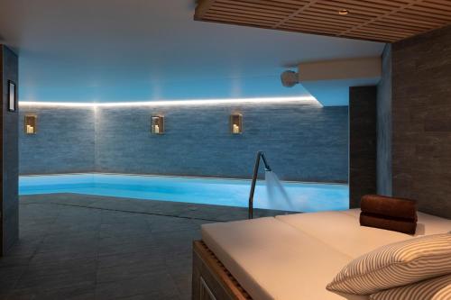 拉克吕萨St-Alban Hotel & Spa的一间卧室设有游泳池、一张床和一把椅子