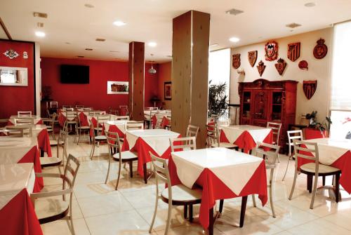 卡卡韦洛斯Hotel Villa de Cacabelos的餐厅拥有红色的墙壁和白色的桌椅