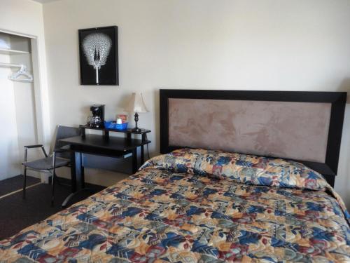 怀特霍斯斯特拉福汽车旅馆的一间卧室配有一张床和一张带床罩的书桌