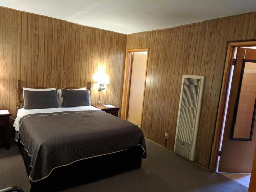 伊莎贝拉湖Lakeview Motel的一间卧室设有一张大床和木墙