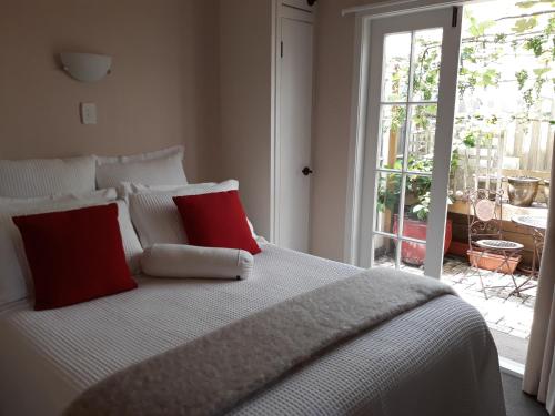 RaetihiRanfurly Cottage的卧室内的白色床和2个红色枕头