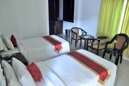 InāniInani Royal Resort的酒店客房带两张床和一张桌子以及椅子。