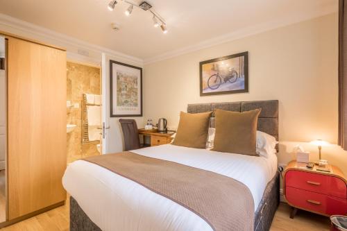 剑桥秋季别墅酒店的一间卧室配有一张大床和红色的行李箱