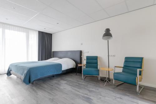 内斯De Berkenhof Aparthotel的一间卧室配有一张床和两张蓝色椅子