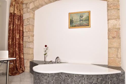 巴特尚道阿尔布雷彻斯伯格公寓式酒店的带浴缸的浴室,墙上有绘画作品