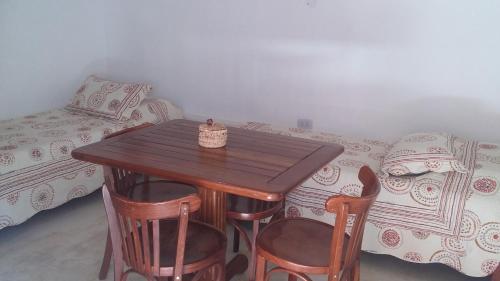 蒂尔卡拉La Cabañita de Tilcara的一张木桌和椅子,位于一个配有床的房间