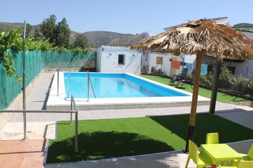 阿尔奇多纳Huerta Espinar - Casa rural con piscina privada的一个带草伞和桌椅的游泳池