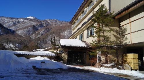 高山Tabist Kazeyuki的山旁的一座积雪的建筑