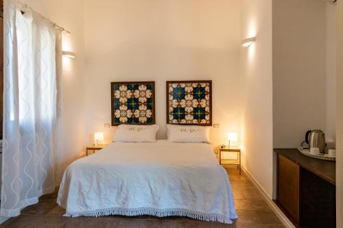 皮亚扎-阿尔梅里纳特里戈纳别墅酒店的卧室配有一张白色床,墙上挂有两张照片