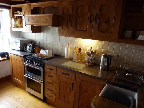 佩伦波斯Engellie Cottage的厨房配有木制橱柜和炉灶烤箱。