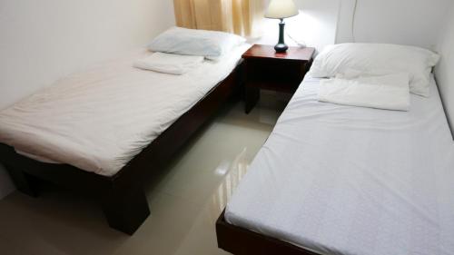 ConsolationJSB Residences Cebu B-flat的带床头柜的客房内的两张单人床