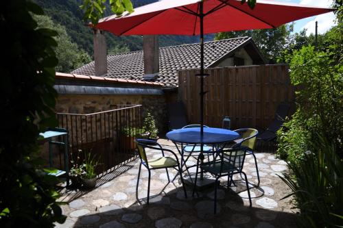VicdessosArcogite的庭院里配有桌椅和红伞